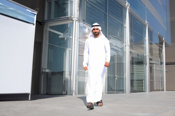 Standing full portrait of Arab Emirati man at a business center with empty shops as background