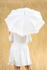 Young woman from behind with white dress and umbrella
