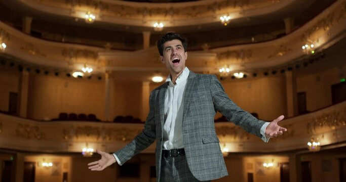 A man sings emotionally in a concert hall Close up portrait, guy in suit gesticulating and singing to audience in theater. Singer hold performance to Audience People Unidentifiable Audience, lifestyle