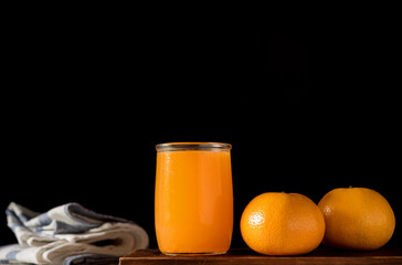 glass of fresh orange juice with fresh fruits on wooden table, high Vitamin C, orange drink, dark background