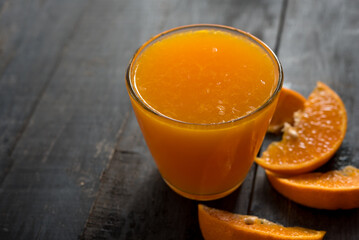 glass of fresh orange juice with fresh fruits on dark wooden table, high Vitamin C, orange drink