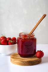 Strawberry jam in the glass jar with fresh berries.