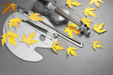 Arts attributes. Violin, bow, art palette, brushes and autumn maple leaves. Autumn mood.