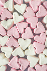 Marshmallow with white and pink hearts on a light background, top view.