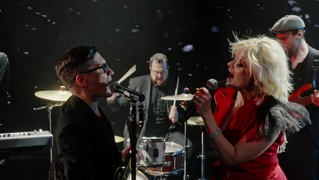 Performers performing together on stage. Male and female singers are singing with band. Musicians having fun in music concert at night.