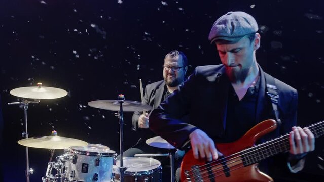 Rock band performing on stage. Male and female singers are singing with musicians. Artists having fun in music concert at night event.