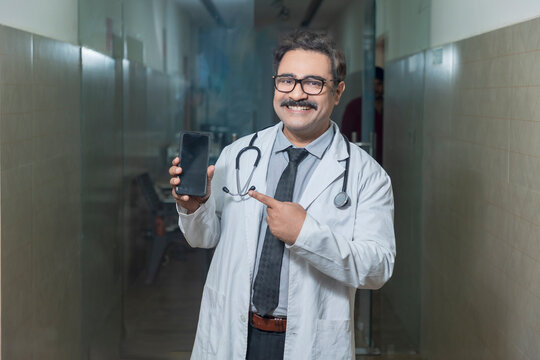 Indian doctor showing smartphone screen at hospital.
