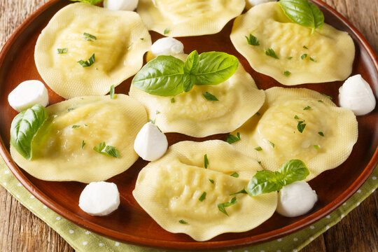 Tasty Italian Cappellacci dumplings with mozzarella and basil closeup on the plate on the wooden table. Horizontal