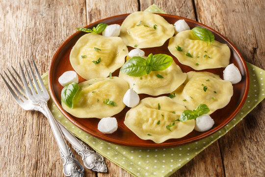 Authentic italian dumplings pasta cappellacci friarielli with mozzarella and herbs close-up in a plate on the table. Horizontal