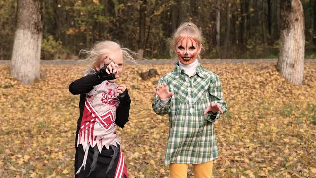 Children girls dressed in Halloween costumes and make up outdoors are having fun. Horizontal video