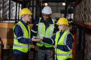 Group of warehouse employees using a digital warehouse management system. logistics manager using a digital tablet while having a meeting with his team.