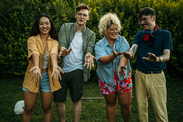 Group of diverse people showing their dirty hands after planting a tree in the garden together.