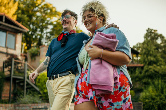 Diverse couple carrying towels and heading for a pool.