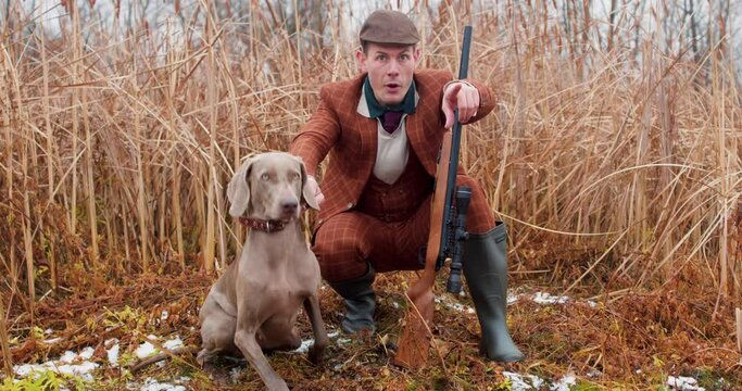 excited smiling happy young man points a finger into the distance. He has found a pray to shoot, successful hunting, weimaraner is running after shooted bird or duck Slow motion