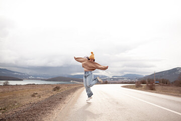 Beutiful woman is wearing jeans, sweater and hat walking in cold weather along the road       ...