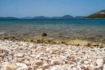 Fototapeta na wymiar A desolated pebble beach on the Adriatic Sea near the city of Dubrovnik. The water is crystal clear with a turquoise color