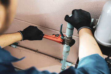 Technician plumber using a wrench to repair a water pump pipe. Concept of maintenance, fix water...