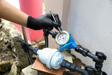 Plumber technician check house water meter gauge valve for bill payment or service maintenance fix pipe water tank drop leak.