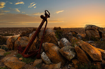 Rusty old anchor forgotten on the beach at sunset