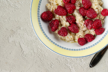 oatmeal with raspberries on a textured background, copy space