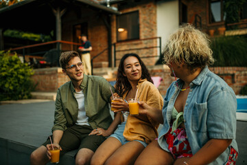 Loving diverse friends sitting, drinking, and talking at the backyard party.