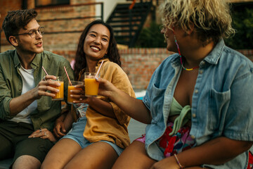 Loving diverse friends sitting, drinking, and talking at the backyard party.