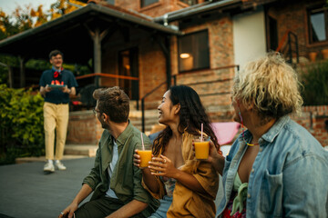 Male host serving slices of watermelon on the plate to his friends in the backyard.