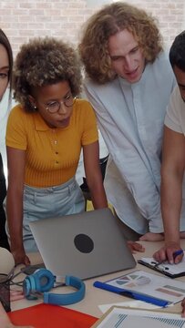 Vertical video. Group of five multi-ethnic workers working in an office or coworking around a table.