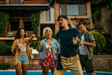 Fototapeta premium Happy friends dancing and enjoying pool party at poolside.