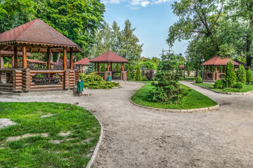 Picnic place in Trostyanets central park in Sumy region, Ukraine. Wooden gazebos with barbecue grills on a green summer lawn with paths