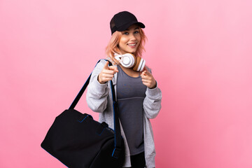 Teenager sport woman with sport bag over isolated background surprised and pointing front