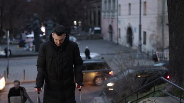 Disabled movement, Prosthetic leg, Artificial limb. Man with prosthetic leg uses aid of handrail while ascending stairs on city street.