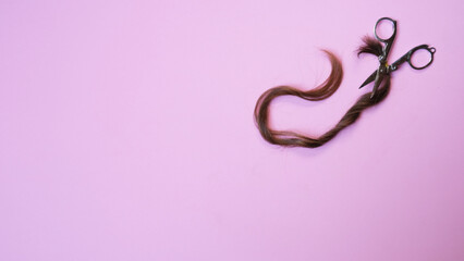 Tijeras con mech&oacute;n de pelo sobre fondo rosa con copyspace