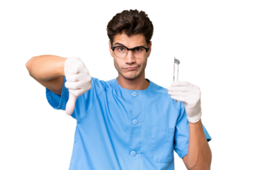 Young dentist man holding tools over isolated background showing thumb down with negative expression