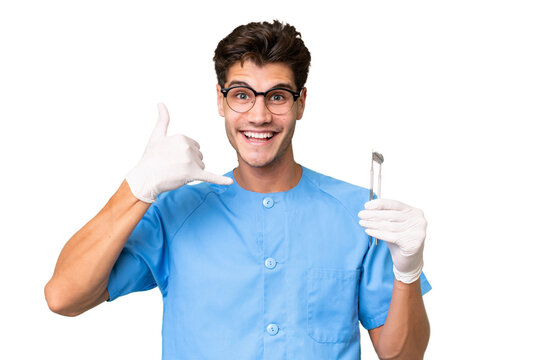 Young dentist man holding tools over isolated background making phone gesture. Call me back sign