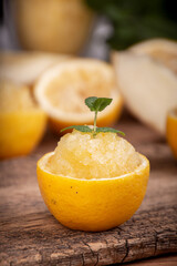 Melon and lemon fruit sorbet. Summer refreshing dessert in half of lemon fruit peel over on old wooden background.