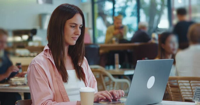 small business concept. beautiful female freelance coffee shop owner is working on Laptop computer checking news cozy cafe. Successful small business owner browsing internet accepting take away orders