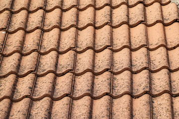 Old roof tiled with dirty wave-shaped clay tiles. Photo in perspective with selective focus