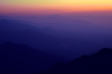 Silhouettes of mountain ranges in the evening haze