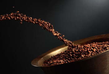 Medium-roasted coffee beans are poured into an old brass roasting pan.