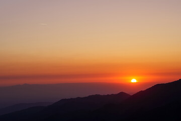 The sun rises over the silhouette of a mountain range