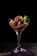 Orange fruit and chocolate ice cream in glass creamer against black backdrop