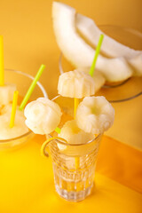 Homemade melon orange fruit sorbet granita popsicles lollies and slices of fresh ripe melon fruit over on yellow background. Top view.  summer dessert, sweet snack.