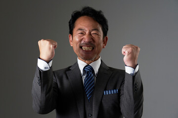ガッツポーズするミドルエイジのビジネスマン　黒背景