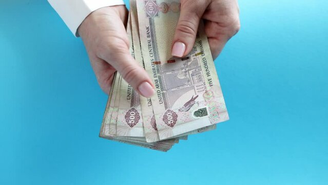 Woman counting AED dirhams in hands, closeup