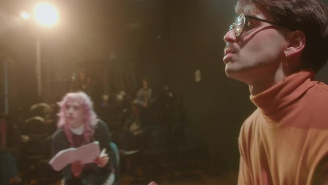 Two emotional actors having dramatic dialogue during rehearsal on theater stage, preparing for performance with female director. PAN shot