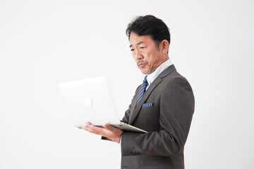 ノートパソコンを使うミドルエイジのビジネスマン　白背景