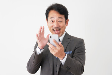 スマートフォンを持って驚くミドルエイジのビジネスマン　白背景