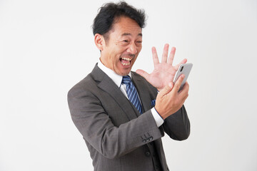 スマートフォンを持って驚くミドルエイジのビジネスマン　白背景