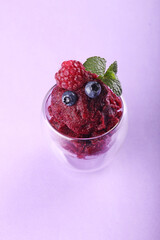Berries sorbet in glasses. Summer refreshing dessert of raspberry, blueberry over on violet color background